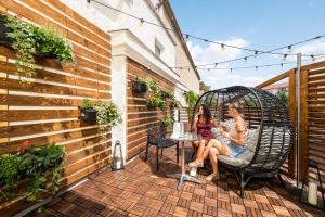 zwei Mädchen sitzen auf einem Stuhl auf einer Terrasse in der Unterkunft Wine & Wellness hotel Besední dům in Valtice