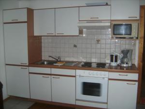 a kitchen with white cabinets and a stove top oven at Gästehaus Verena in Mondsee