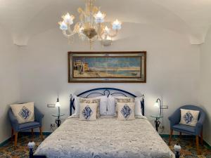 a bedroom with a bed with a chandelier and two chairs at Villa Le Baste in Furore
