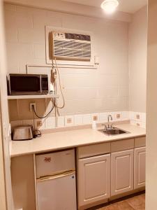 a kitchen with a sink and a microwave at Red Carpet Inn & Suites in Calgary