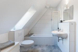 ein weißes Bad mit einem WC und einem Waschbecken in der Unterkunft Ferienapartments Neustadt in Holstein in Neustadt in Holstein