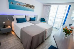 a hotel room with two beds with blue pillows at Anonymous Beach Hotel (Adults 16+) in Ayia Napa