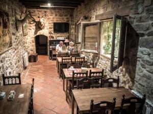 two people in a restaurant with wooden tables and chairs at Castillo de Añón de Moncayo in Añón
