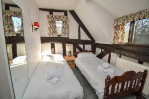 two beds in a room with two windows at The Game Keepers Cottage in Welwyn