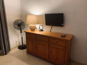 einen Fernseher auf einem Holzschrank mit Lampe in der Unterkunft Résidence Figarella in Propriano