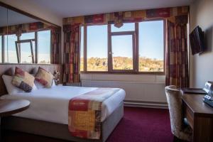 una camera d'albergo con un letto, una scrivania e due finestre di West County Hotel a Chapelizod