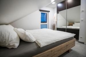 a bedroom with a bed with white sheets and a mirror at Mein Beach House in Löbnitz