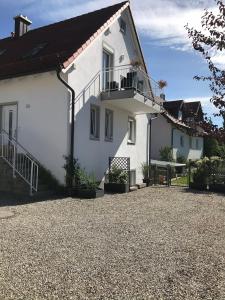 a white house with a balcony and a gravel driveway at Ferienwohnung im Herzen der Holledau in Pörnbach