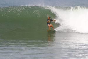 Un hombre montando una ola en una tabla de surf en el océano en Tropical Sunday Bungalow - Surf And Stay, en Selong Belanak