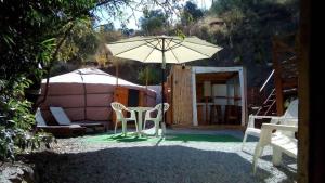 um pátio com uma mesa, um guarda-chuva e uma tenda em Eldorado Yurt em Algarrobo