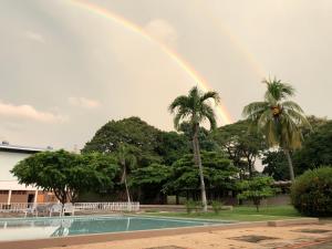 een regenboog boven een zwembad met palmbomen bij Hotel Diriá Santa Cruz in Santa Cruz