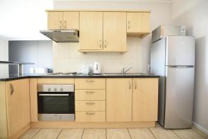 a kitchen with wooden cabinets and a refrigerator at The Island Club Apartment in Cape Town