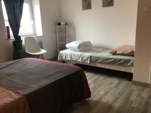 a bedroom with two beds and a chair and a window at la menuiserie in Jeuxey