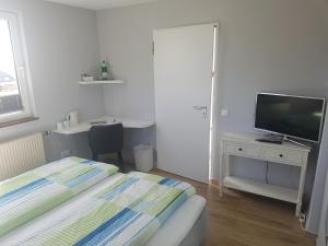 Schlafzimmer mit einem Bett und einem Schreibtisch mit einem TV in der Unterkunft Venngasthof Zur Buche in Monschau