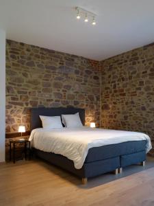a bedroom with a bed with a brick wall at Le Merle - Bois-de-Villers in Profondeville