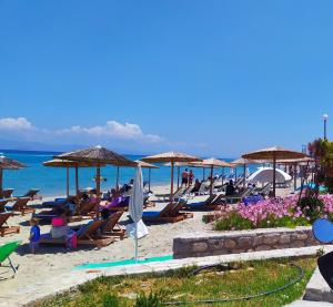 a beach with people sitting in chairs and umbrellas at Del Soll in Polychrono