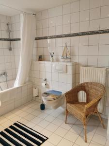 a bathroom with a toilet and a tub and a chair at Vogelhus Garz in Garz