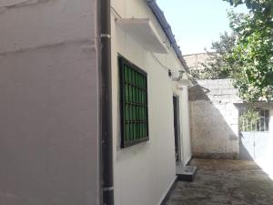 ein weißes Gebäude mit einem Fenster mit grünen Balken in der Unterkunft Joli Chalet plain-pied avec jardin privatif in Tlemcen