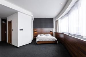 a bedroom with a bed, a desk and a window at Tempus Club Garni Hotel in Bratislava