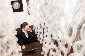 una mujer hablando en un celular delante de filas de gafas en Opera Garden Hotel & Apartments, en Budapest