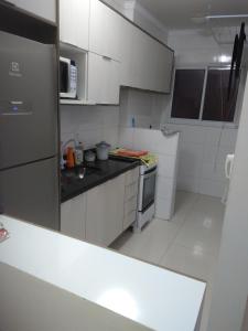 a kitchen with white cabinets and a black counter top at Apto Praia Grande - Guilhermina in Praia Grande