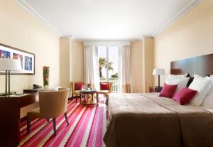 a hotel room with a large bed and a desk at Hôtel Juana in Juan-les-Pins