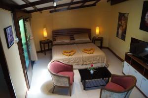 a bedroom with a bed and two chairs and a television at Khaolak Relax Eco Resort in Khao Lak