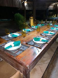 een houten tafel met borden en wijnglazen erop bij Sunset House Pontal de Maracaípe in Porto De Galinhas