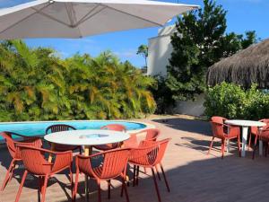 een patio met tafels en stoelen naast een zwembad bij Sunset House Pontal de Maracaípe in Porto De Galinhas