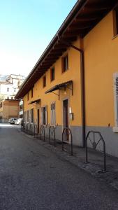 un edificio amarillo con una fila de puertas al lado de una calle en B&B Le Muse, en Trento