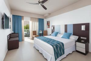 a bedroom with a large white bed with blue pillows at Hotel Riu Costa del Sol - All Inclusive in Torremolinos