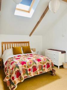 a bedroom with a bed with a floral bedspread and a window at Vinegar Hill Pottery in Lymington