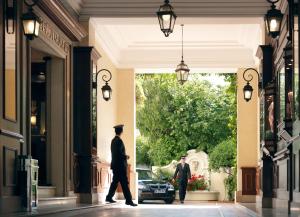 two men walking down a street with a car in a doorway at Hôtel Juana in Juan-les-Pins