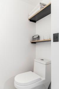 een witte badkamer met een toilet en een plank bij Hotel Itto Condesa in Mexico-Stad