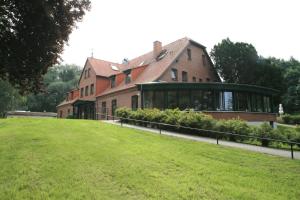 ein großes Backsteinhaus mit grünem Rasen davor in der Unterkunft Seehotel Heidehof in Klein Nemerow