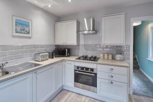 a kitchen with white cabinets and a stove top oven at Host & Stay - Fly Away at Ruby in Saltburn-by-the-Sea