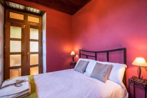 a bedroom with a white bed and a red wall at El Balcón De Muniellos in Oballo