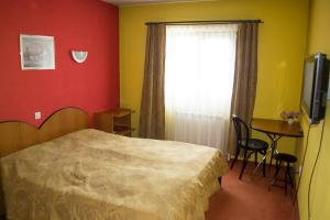 a bedroom with a bed and a table and a window at PENSIUNEA MURY in Braşov
