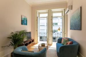 uma sala de estar com duas cadeiras azuis e uma televisão em LovelyStay - 2BR Flat with AC in Duque de Loulé no Porto