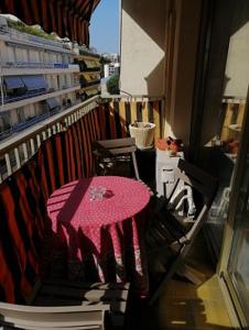 a balcony with a pink table and chairs on it at Grand 2 pièces Centre ville Antibes in Antibes