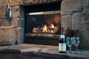 a bottle of wine and two wine glasses in front of a fireplace at Strong House Inn in Vergennes