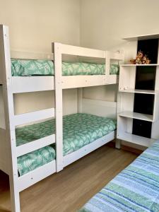 two white bunk beds in a room at Apart. Manacá (Próximo a pista e rodoviária de Mogi Mirim). in Mogi Mirim