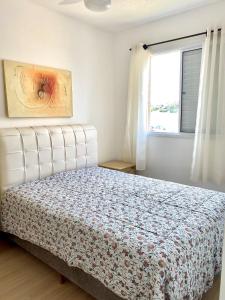 a white bedroom with a bed and a window at Apart. Manacá (Próximo a pista e rodoviária de Mogi Mirim). in Mogi Mirim