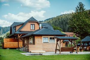 une maison en bois avec un kiosque et un banc dans l'établissement Valašský dvůr, à Velké Karlovice