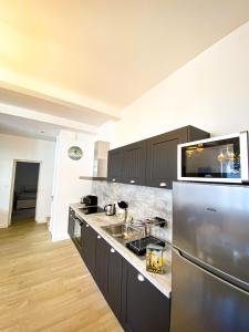 a kitchen with a stainless steel refrigerator and a sink at APT bord de Mer, hypercentre Dinard, Parking prive in Dinard