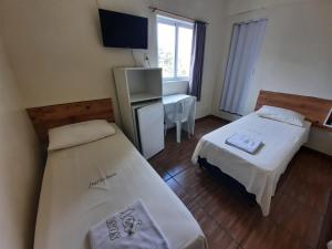 a hotel room with two beds and a desk at Hotel Três Passos - Prox ao Aeroporto e Rodoviária in Porto Alegre