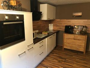 cocina con armarios blancos y microondas en Pension Ba-Bett's en Markt Erlbach