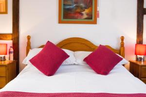 a white bed with two pink pillows on it at Moss Cottage in Stratford-upon-Avon
