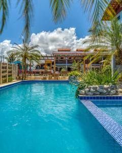 a swimming pool in front of a building with palm trees at Pousada Blue Viking in Praia do Frances