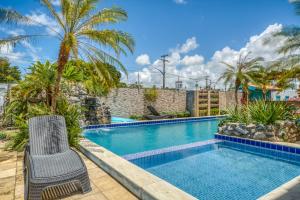 a swimming pool with two chairs and palm trees at Pousada Blue Viking in Praia do Frances